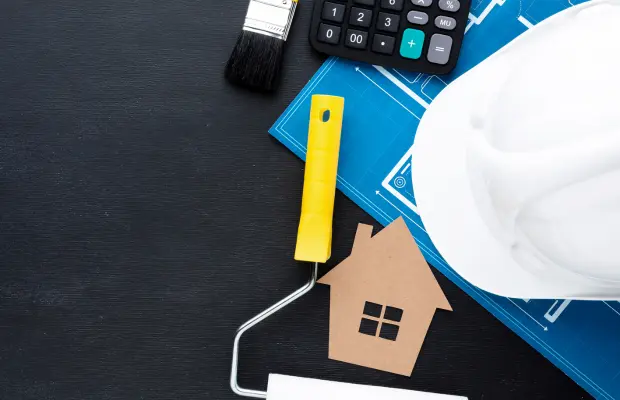 Construction tools alongside house blueprints on a table.