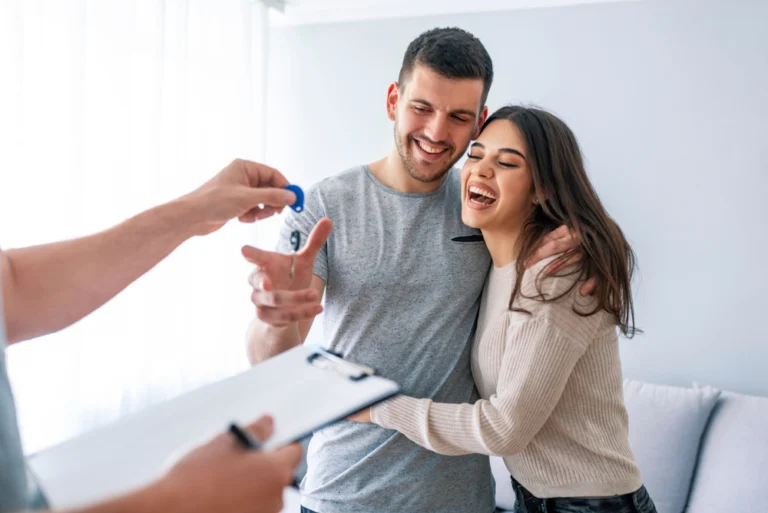 Happy couple receiving house keys from a real estate agent.