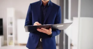 A real estate agent in a blue suit assessing a property with a clipboard in hand.